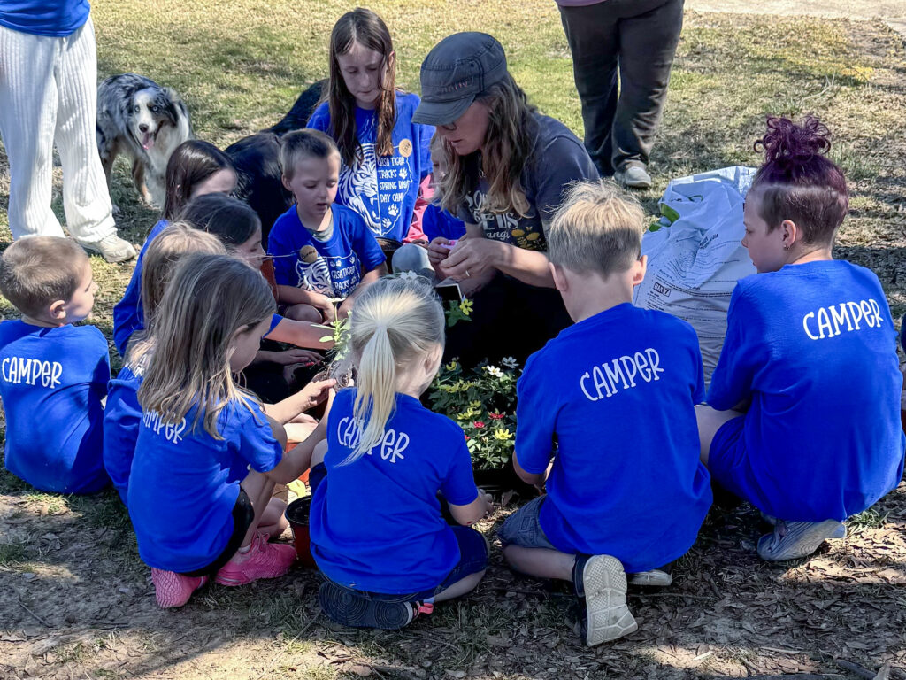 Camp leader showing flowers to summer camp kids wearing blue T-shirts