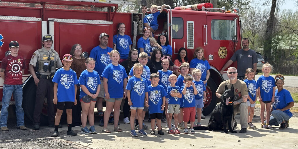 A group of summer campers and emergency responders pose in front of a fire truck in Casa.